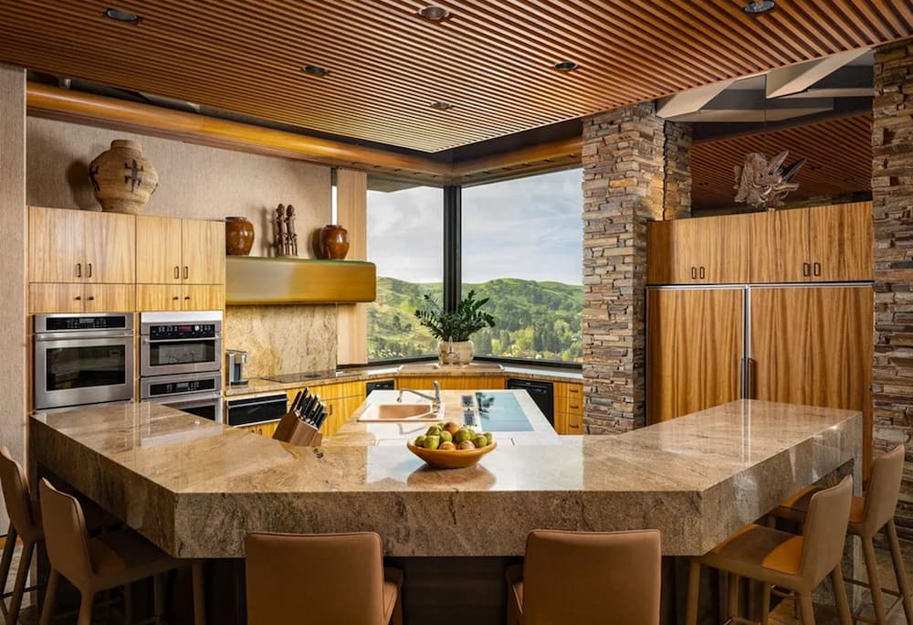 Modern kitchen with vaulted ceiling, wood beams, open shelving, and round dining table