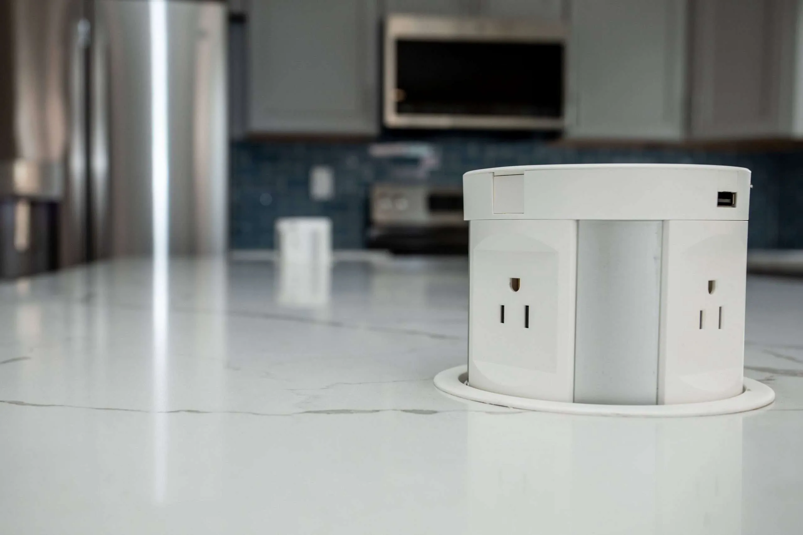 Pop-up power outlet with USB port installed in a white marble kitchen countertop