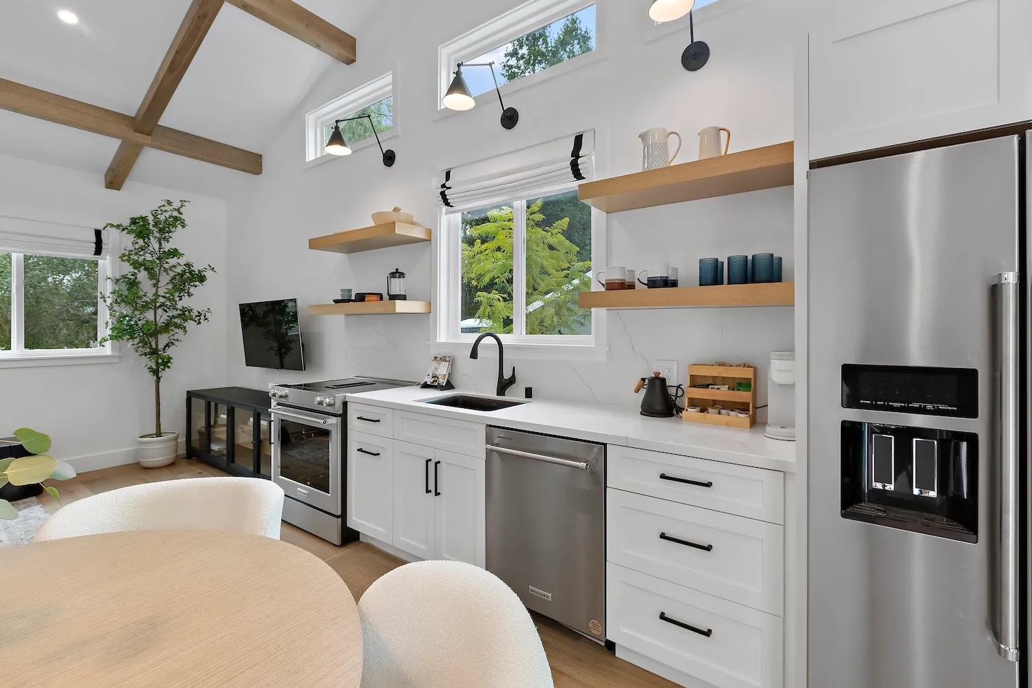 Contemporary kitchen with white cabinetry, wood accents, stainless steel appliances, and natural light from multiple windows including clerestory windows