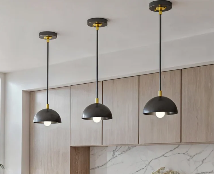 Three dome pendant lights hanging over a kitchen