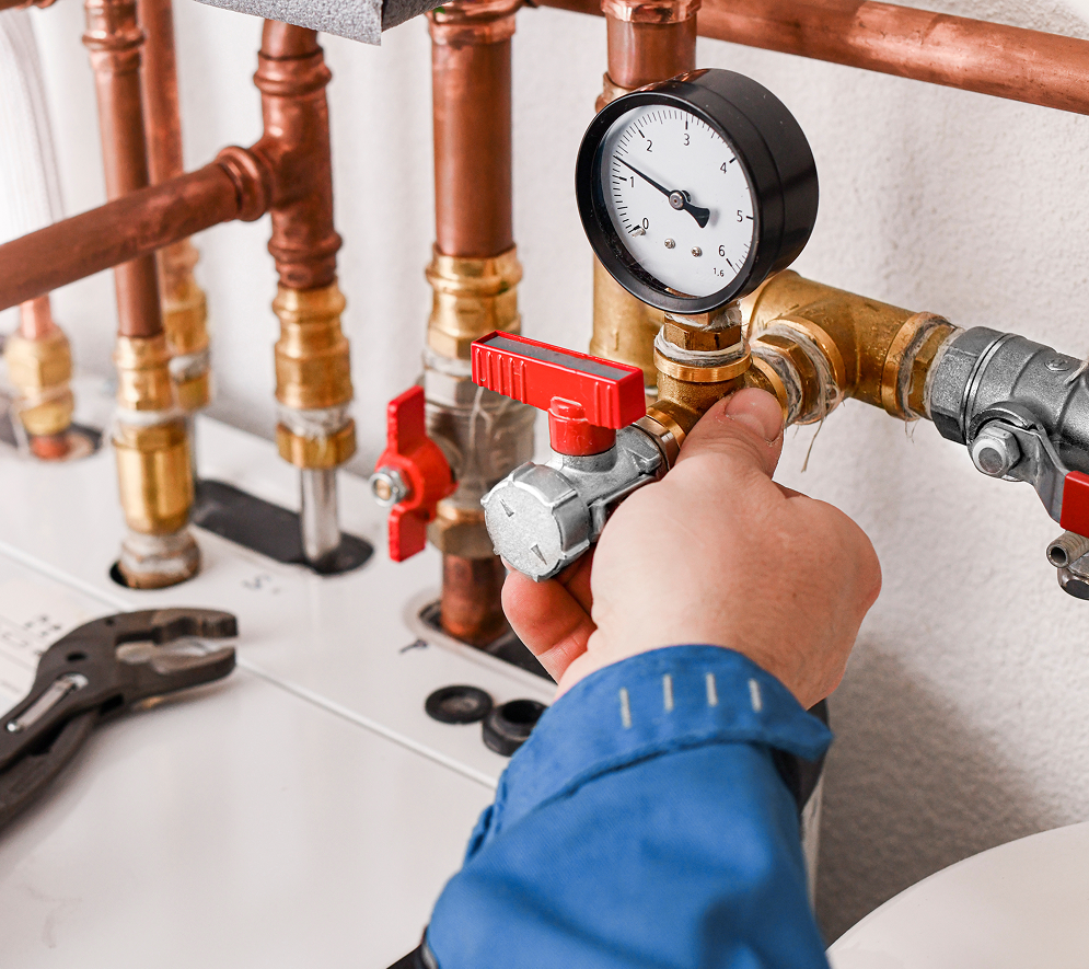 Plumber installing copper pipe fittings with a pressure gauge