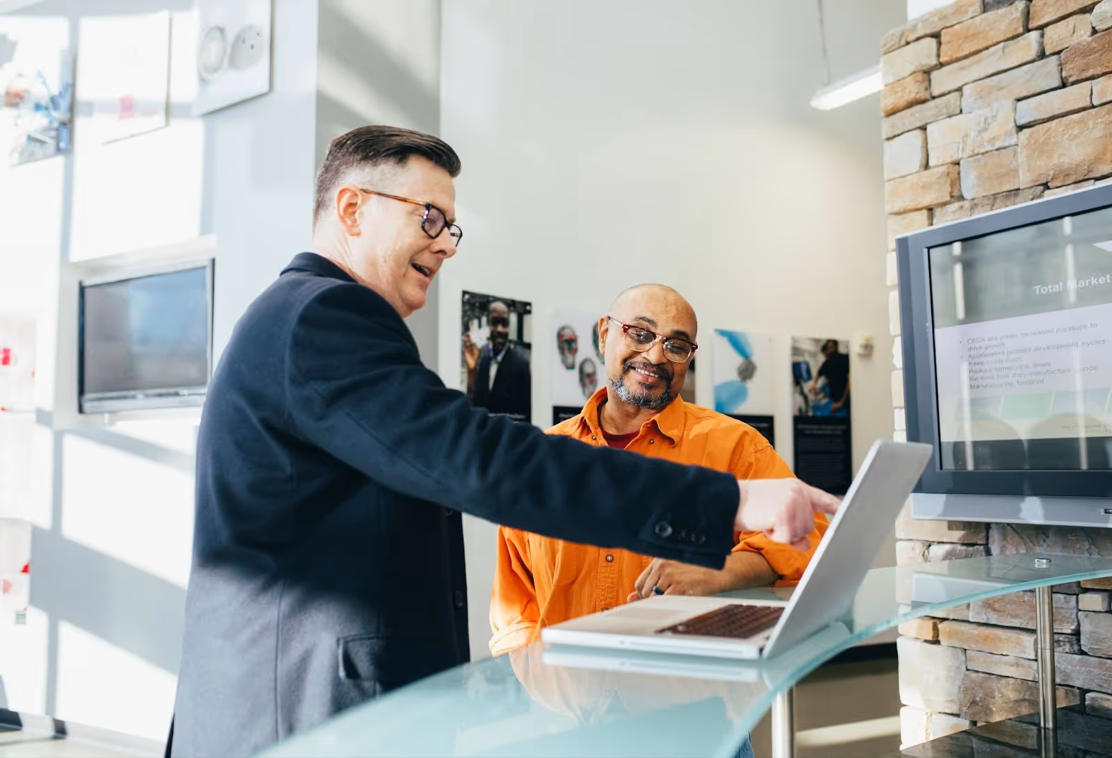 Alt - A man pointing to a laptop screen in front of another man. Source - Pexels