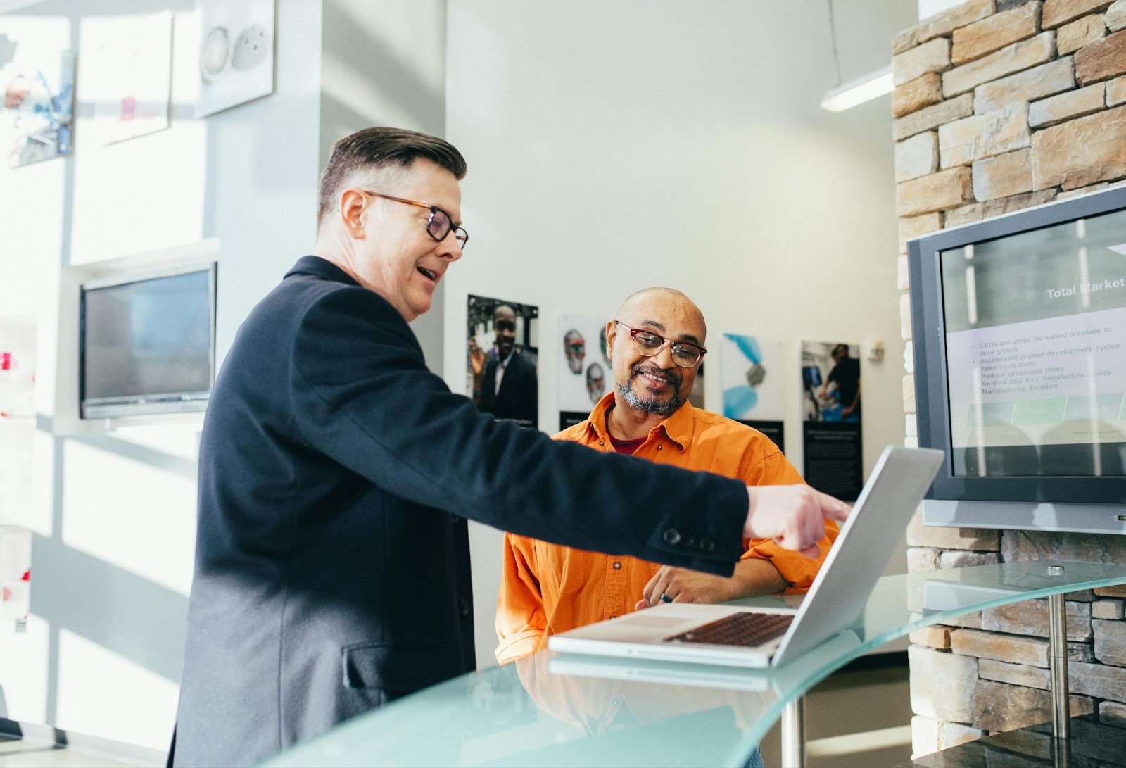Alt - A man pointing to a laptop screen in front of another man. Source - Pexels