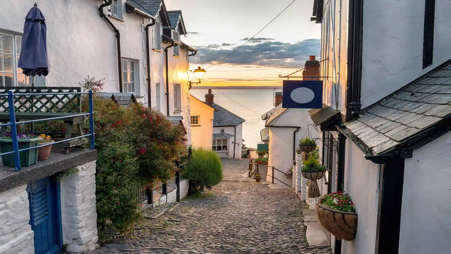 Cobbled street in the coastal village of Clovelly, Devon, with whitewashed cottages and sea views at sunset