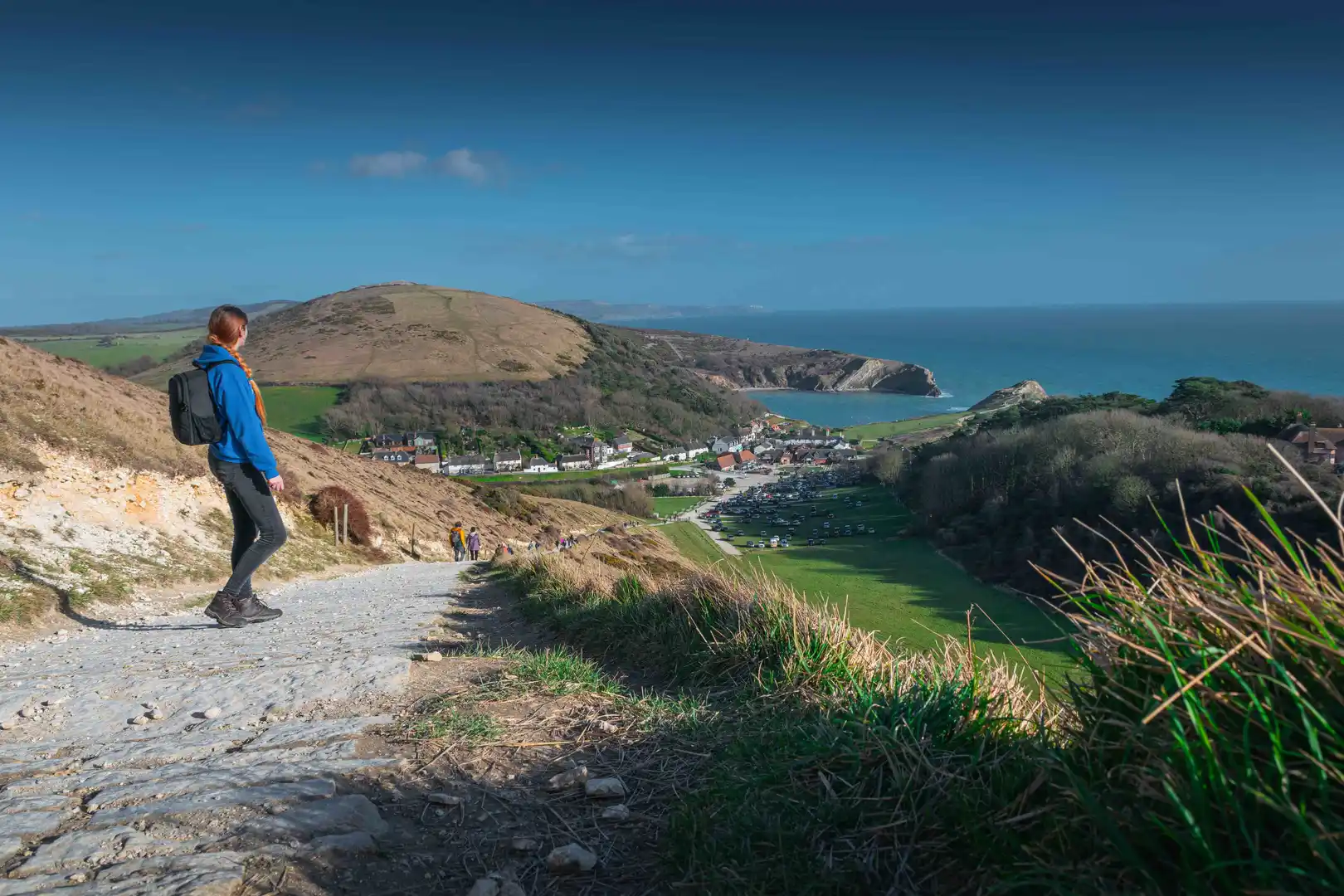 Girl in blue hoodie and with the black backpack looks on the Lulworth Cove, Jurassic Coast, Dorset, UK