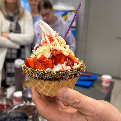 Fertig garniertes Softeis in Waffelbecher mit frischen Erdbeeren, Streuseln und weißen Schokoraspeln