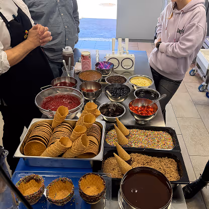 Übersicht der Topping-Station beim ETC Softeis-Seminar mit Saucen, Streuseln, Früchten und Waffeltüten