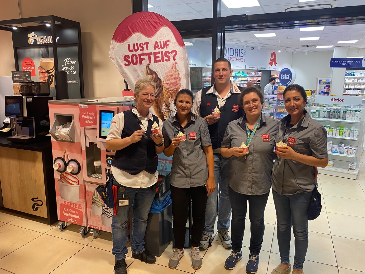 Team mit Softeisbechern neben einem Softeisautomaten im Markt