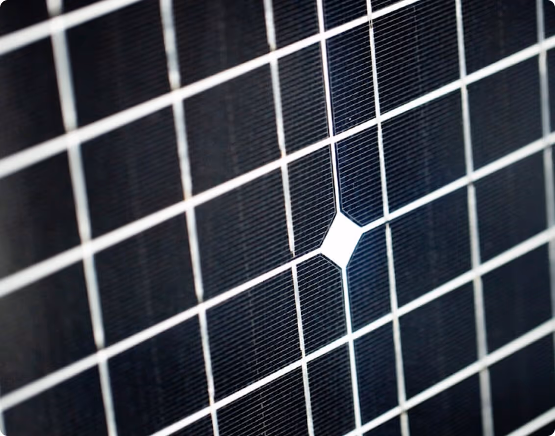 Extreme close-up of a black solar panel cell grid showing surface texture and reflection