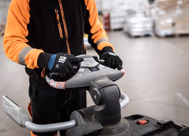 A logistics worker in high-visibility gear operating warehouse equipment, symbolising the operational level where LONGi raises ESG standards — screening 100% of new suppliers and conducting on-site audits to verify environmental and social performance.
