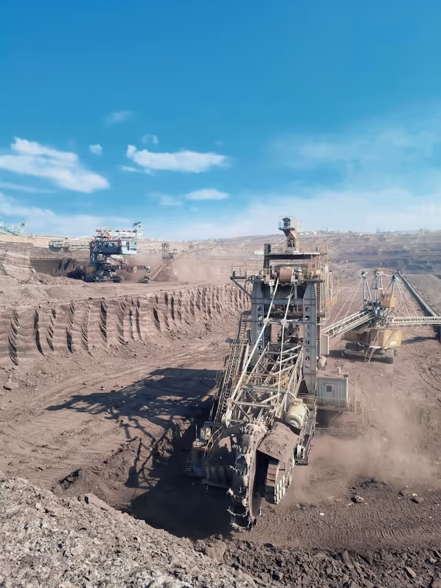 A large open-pit mining operation with heavy excavation equipment, representing the upstream material extraction that higher-efficiency solar modules help reduce — fewer modules per system means lower demand for raw materials and balance-of-system components.