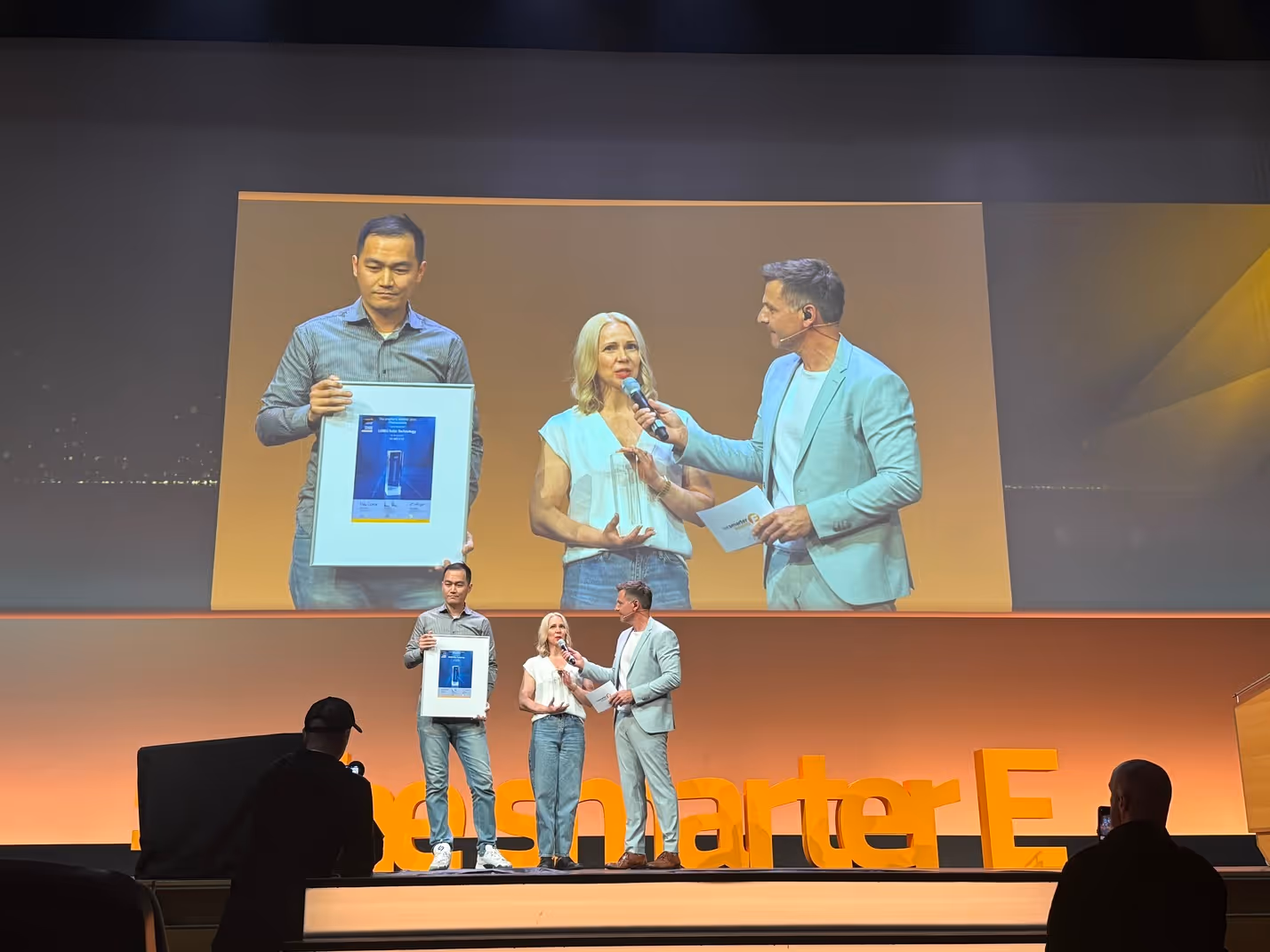 LONGi team receiving the Intersolar Award 2025 on stage, holding the framed certificate during the live ceremony