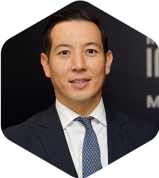 Portrait of speaker Alibek in a dark suit and tie.