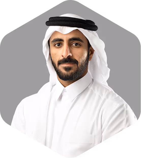 Portrait of a man wearing a white thobe and white ghutra with a black agal against a gray background.