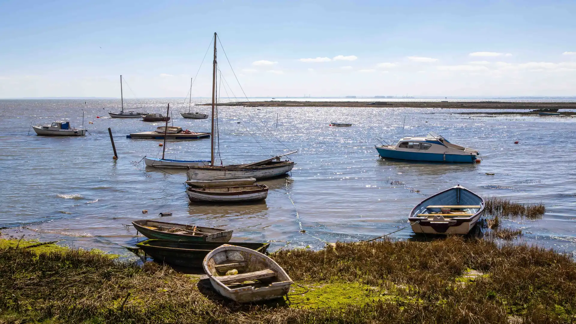 Small boats resting along the saltmarsh coast of Essex — tidal water, soft light, and peaceful estuary walking.