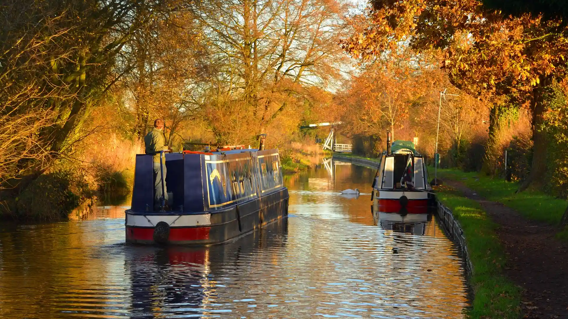 Narrowboats moored on the Llangollen Canal at Wrenbury, Cheshire, with autumn trees reflected in the water