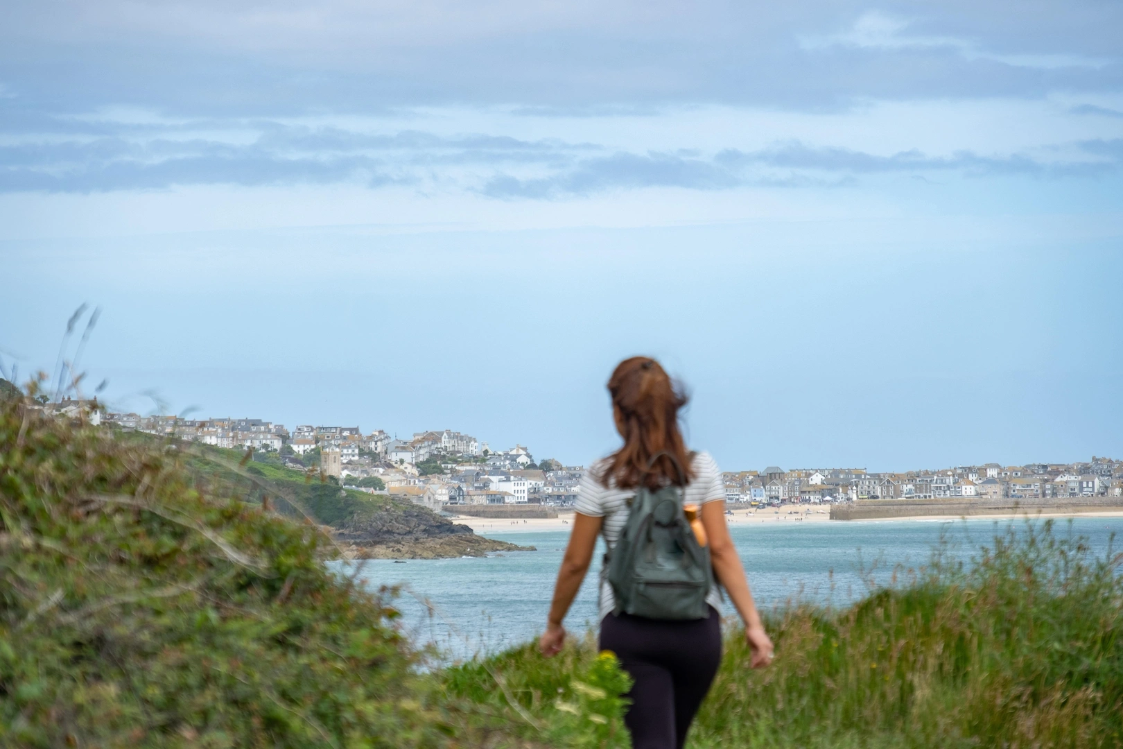 Woman walking on the South West Coastal Path in Cornwall, England with St Ives in the background