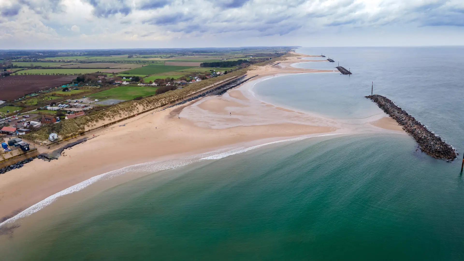 Aerial view of Sea Palling Beach on the Norfolk coast, showing sandy shoreline, sea defences, and surrounding countryside under a cloudy sky.