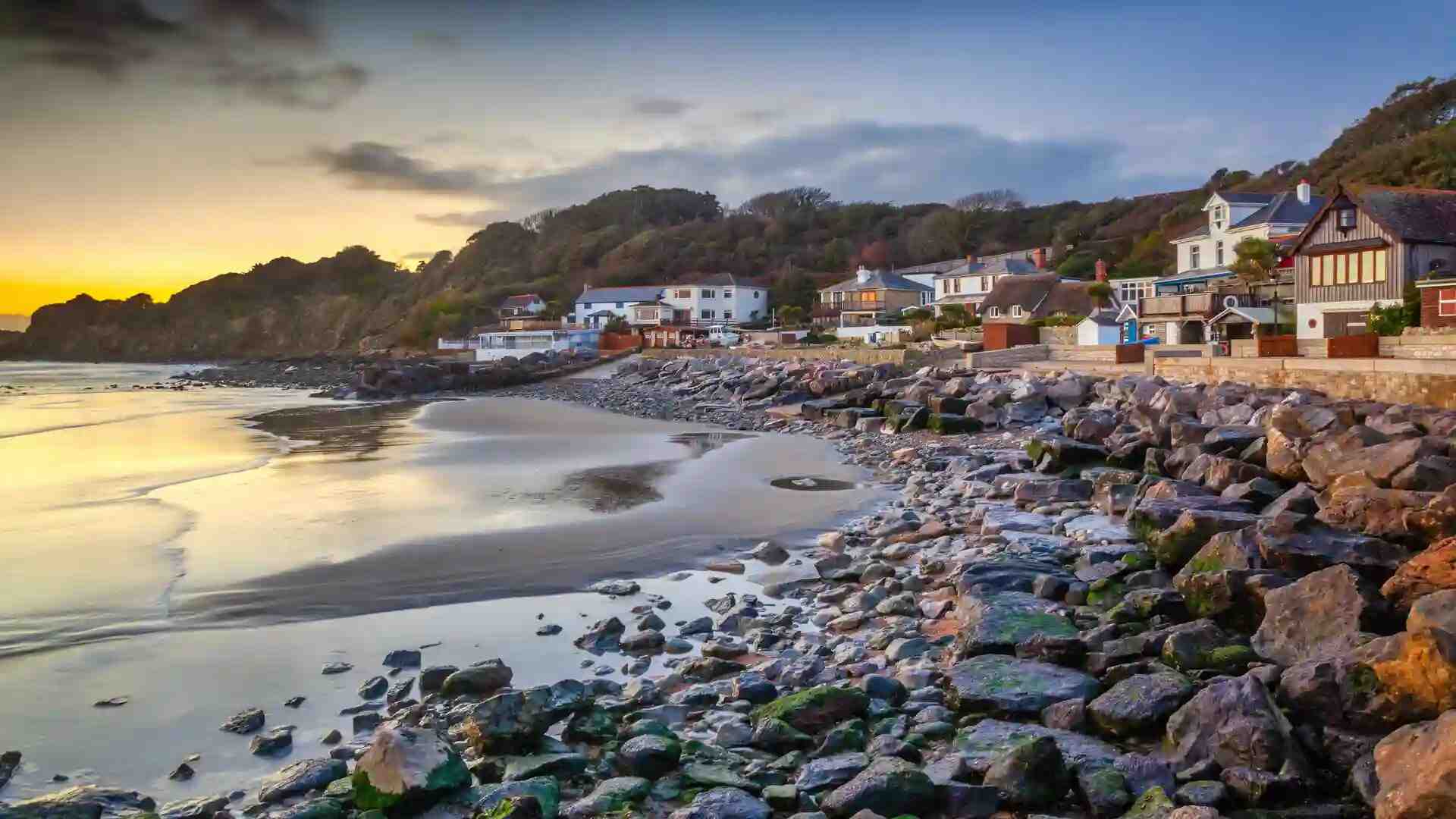 Rocky shoreline and sandy beach at sunset in a seaside village on the Isle of Wight, South East England.