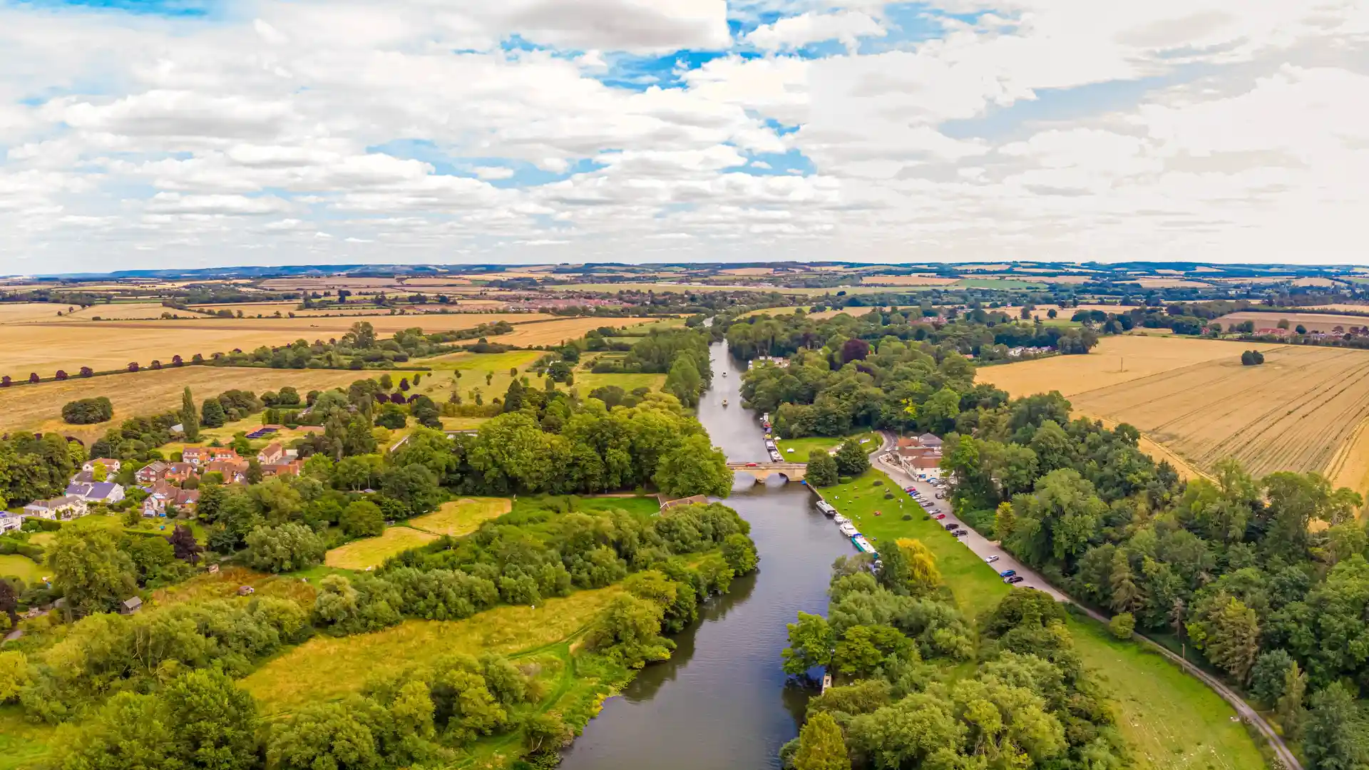 The River Thames winding through Shillingford in Oxfordshire, with boats, fields, and riverside houses.
