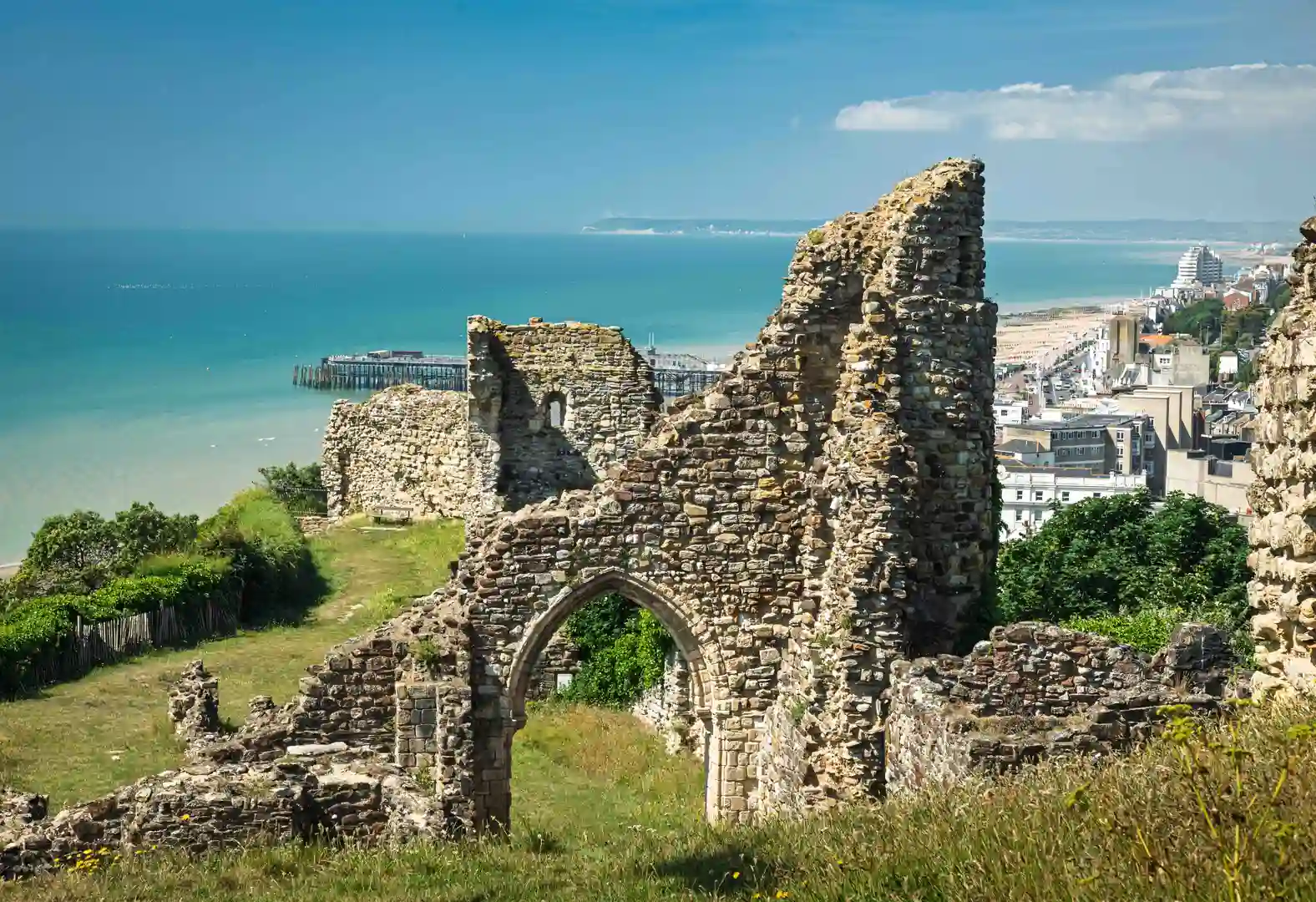 Alt text: Ruins of Hastings Castle overlooking the sea and town of Hastings, East Sussex, with the coastline and pier visible along the Saxon Shore Way trail.