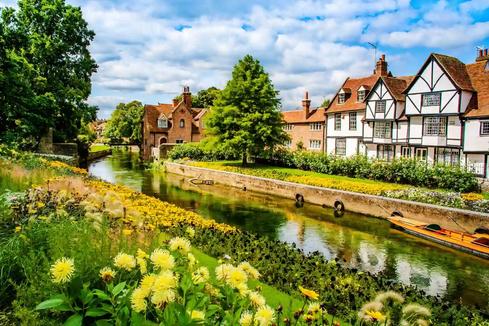 Colourful riverside gardens and historic timber-framed houses along the River Stour in Canterbury, Kent, England.