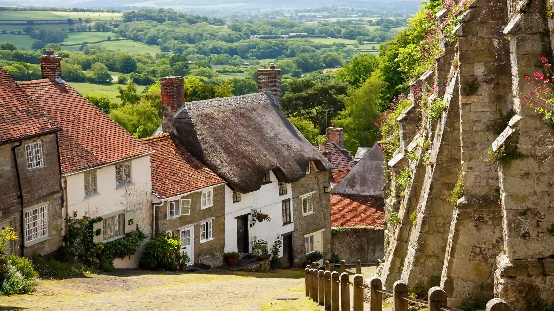 Cobbled Gold Hill in Shaftesbury with thatched cottages and countryside views, Dorset, South West England.