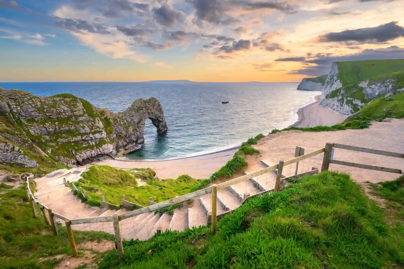 Durdle Door limestone arch on the Jurassic Coast in Dorset, England, viewed from clifftop steps at sunset.