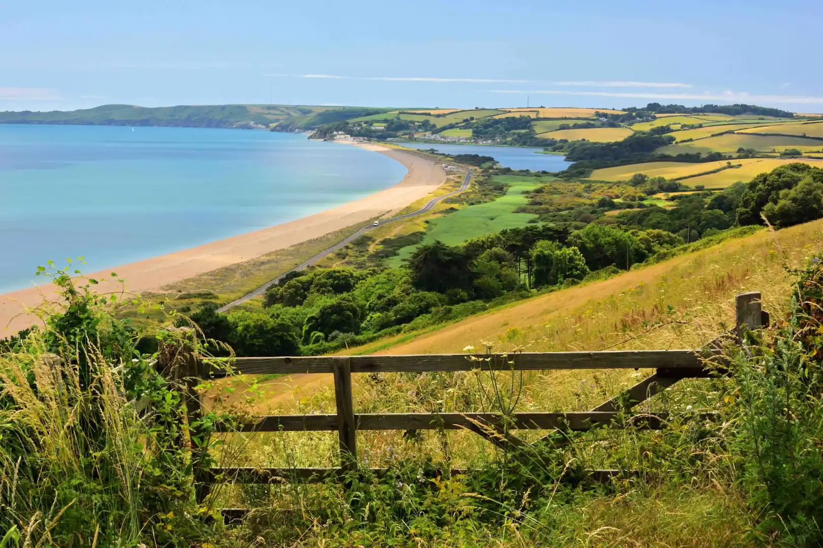 View over Start Bay and Slapton Sands on the South West Coast Path in South Devon, with rolling farmland, sandy beach, and sea cliffs.
