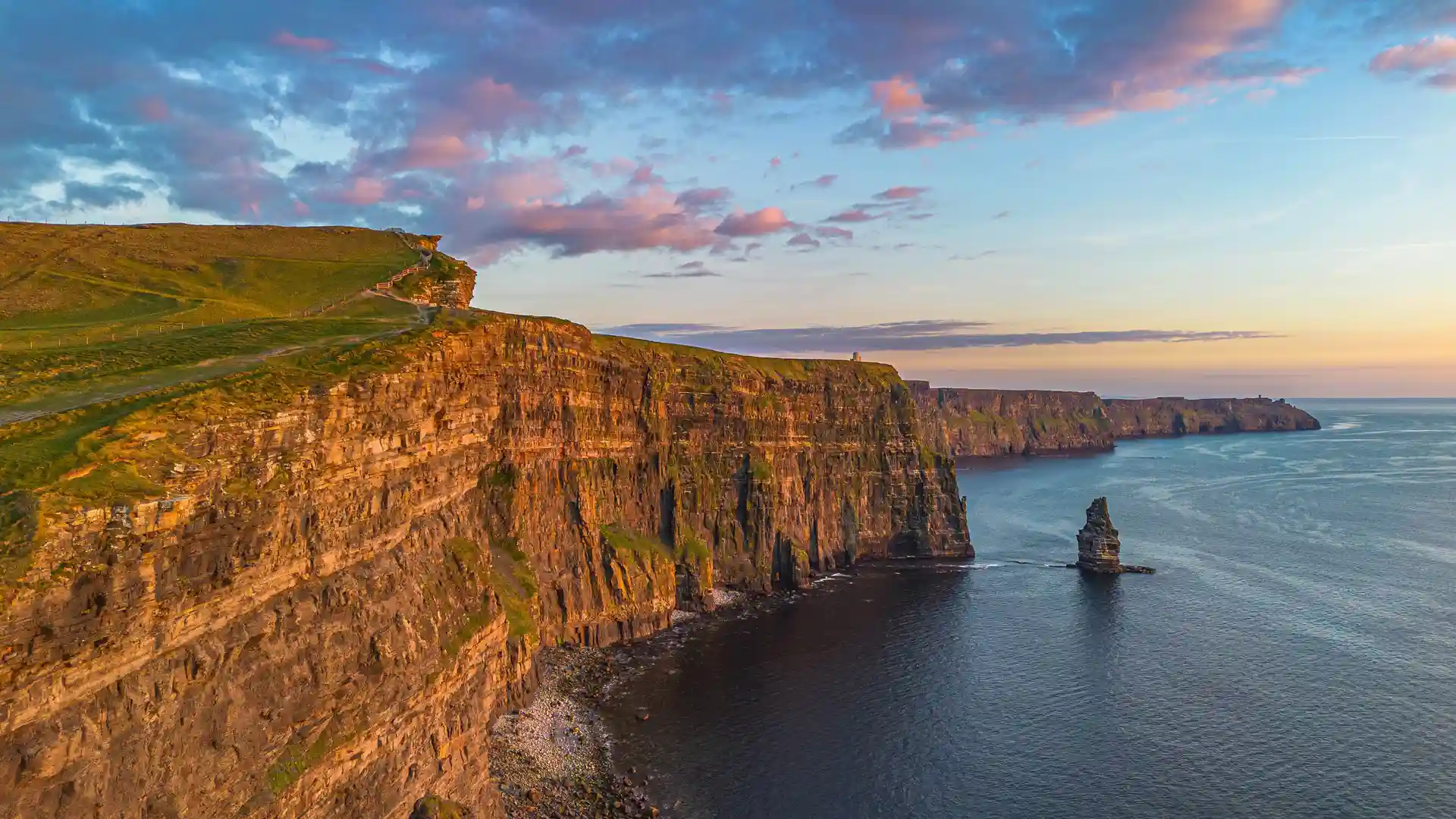 Sunset over the Cliffs of Moher in County Clare, Ireland, with dramatic sea cliffs, coastal walking trail, and Atlantic Ocean views.