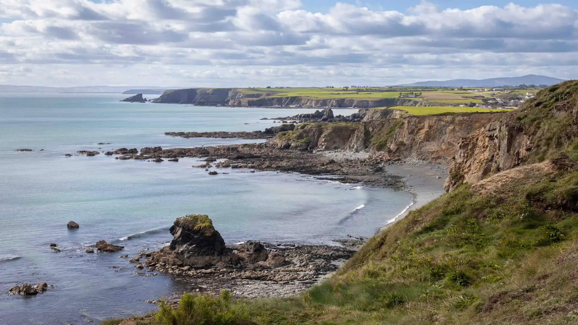Rocky cliffs and coves along the Copper Coast in County Waterford, Ireland, part of the UNESCO Global Geopark and a popular walking trail destination.