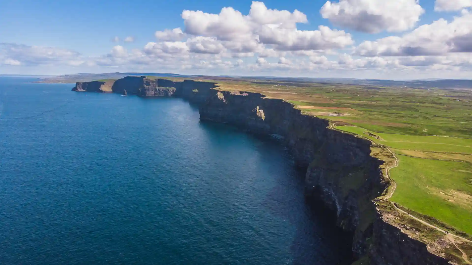 The Cliffs of Moher rising above the Atlantic Ocean with layered limestone cliffs, sea stack, and dramatic coastal views in County Clare, Ireland.