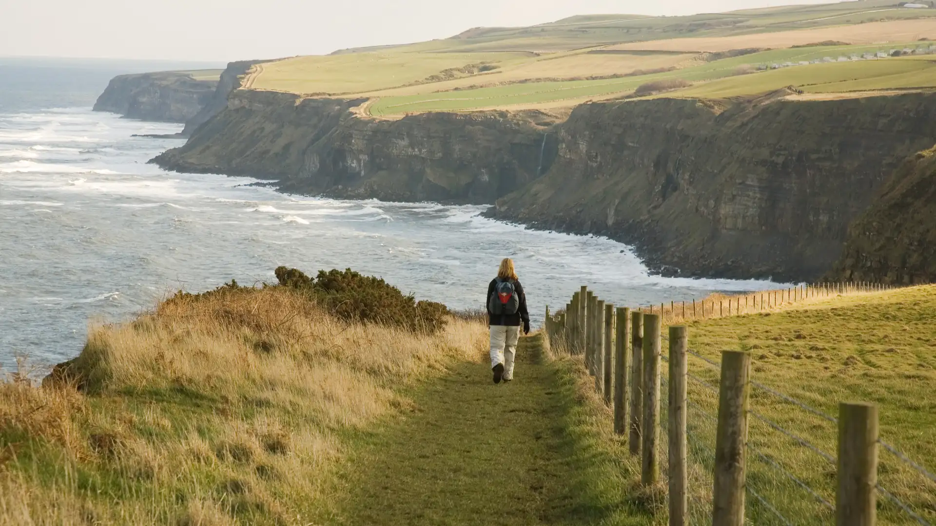 Walker on the Cleveland Way along the Yorkshire coast, overlooking cliffs and the North Sea in North Yorkshire, England.