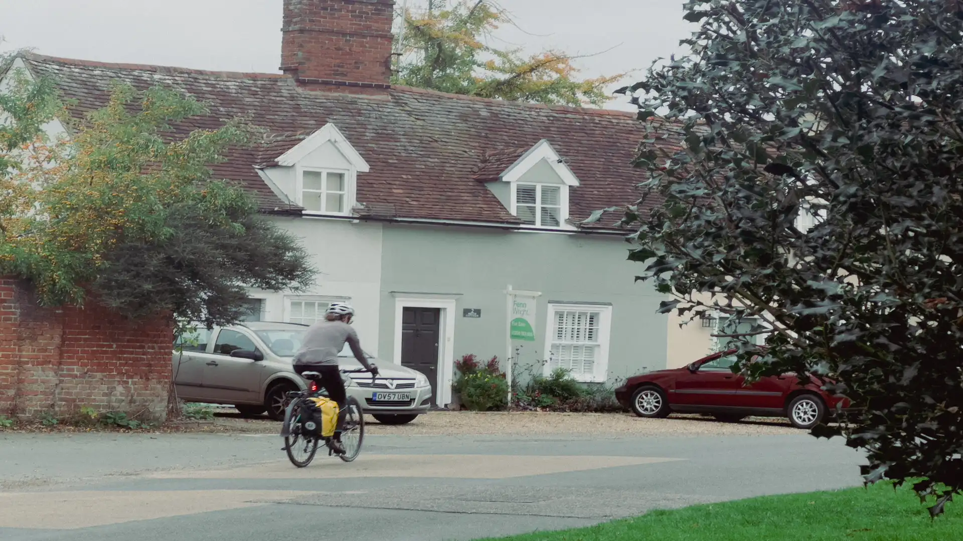 A cyclist rides through a quiet Suffolk village near Dedham Vale, passing traditional cottages on a calm autumn day — part of the region’s focus on improving walking, cycling, and wheeling routes.
