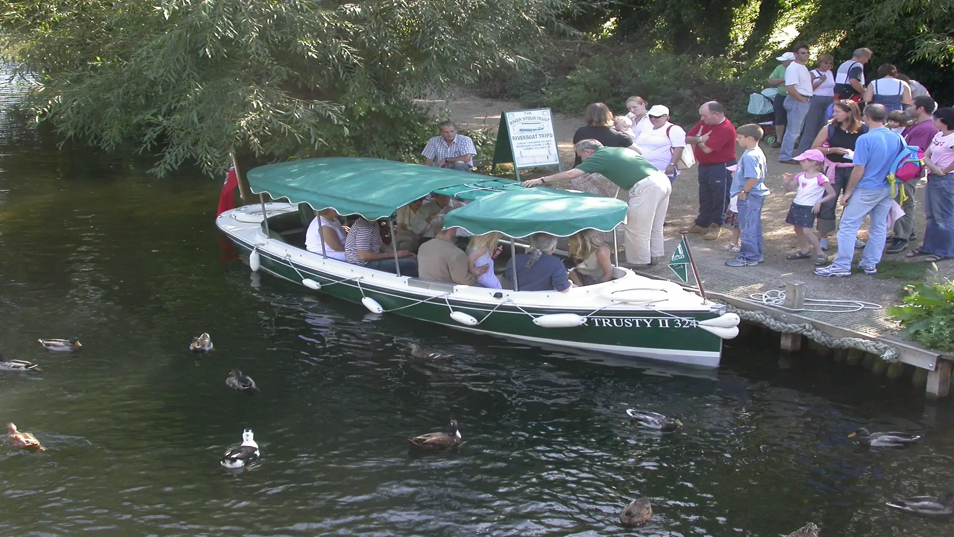 Passengers boarding an electric boat operated by the River Stour Trust on the River Stour in Dedham Vale.