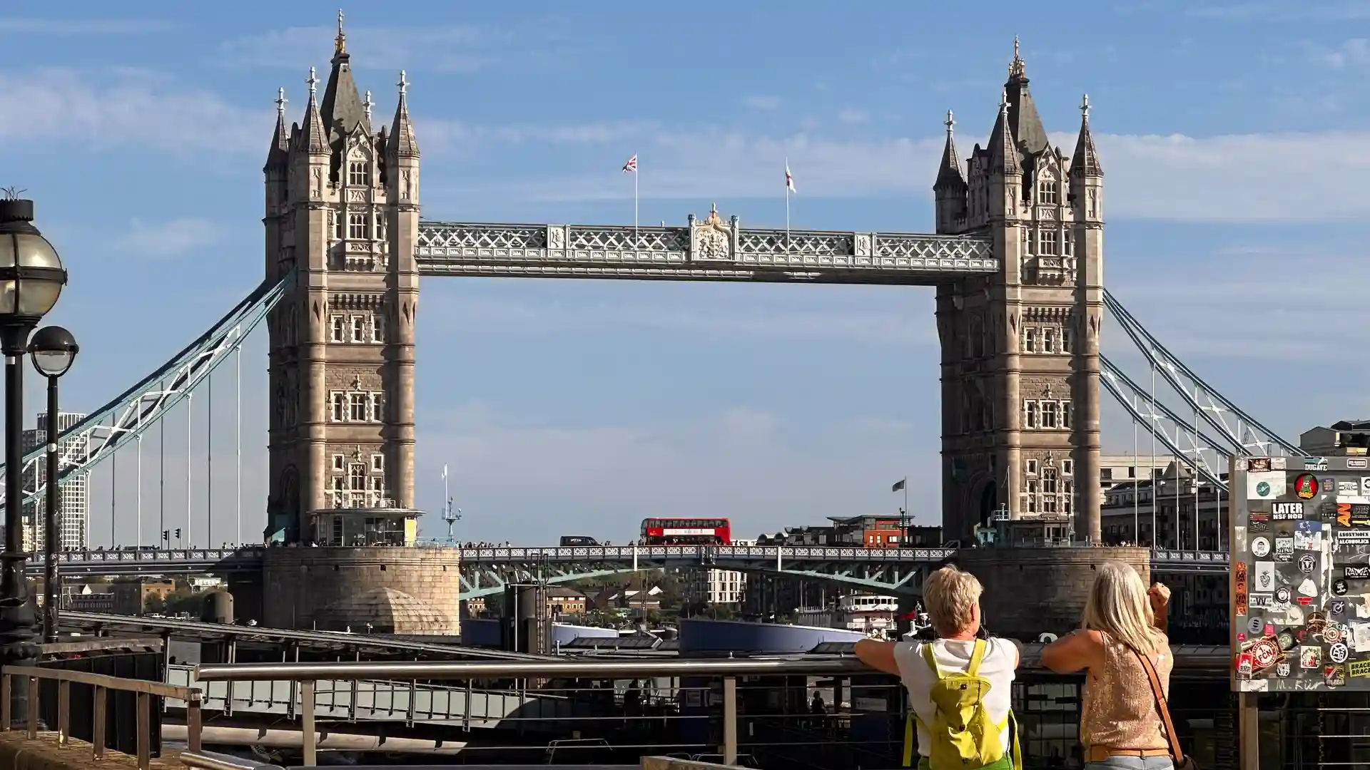 Walkers enjoying a riverside viewpoint of Tower Bridge on the Thames Path in London.