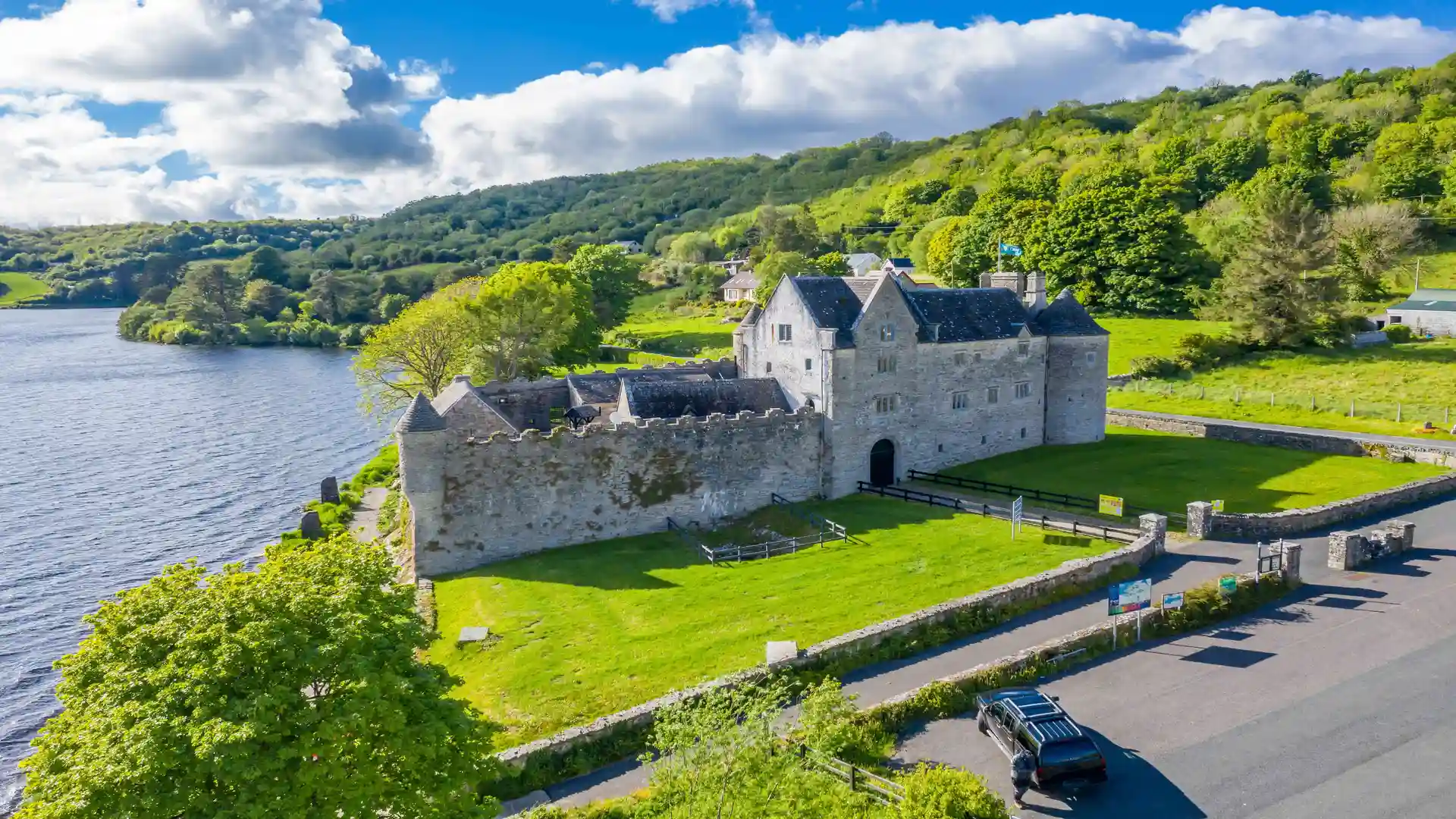 Aerial view of Parke’s Castle on the shores of Lough Gill in County Leitrim, Ireland’s Hidden Heartlands, with forested hills and lake reflections.