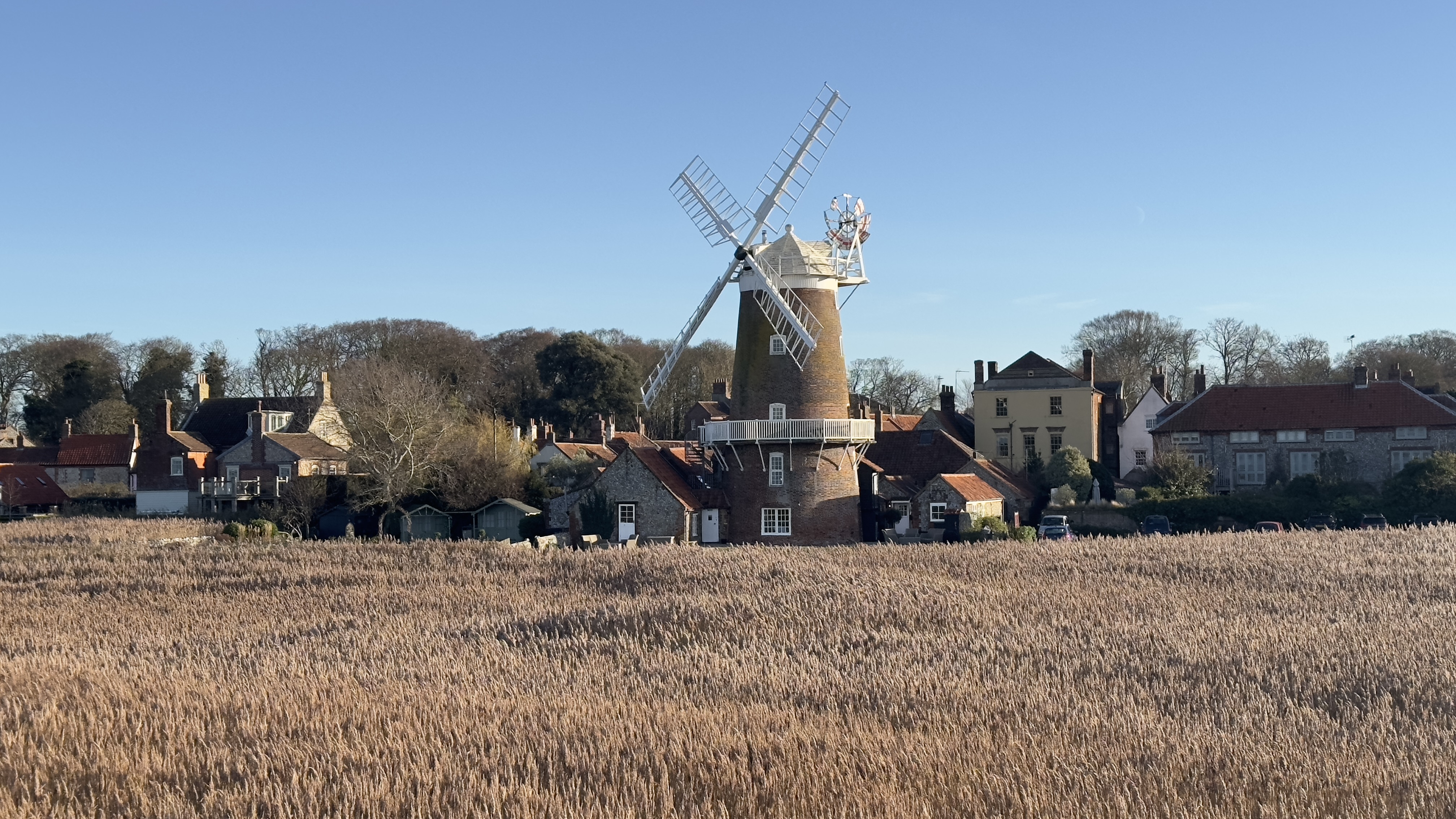 Cley Windmill overlooking the saltmarshes at Cley-next-the-Sea on the Norfolk coast, with village houses behind.