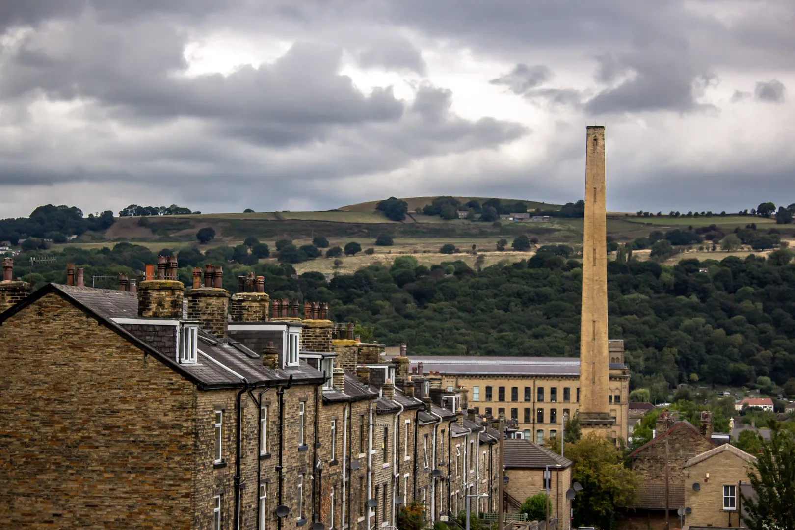 Victorian terraced houses and Salts Mill chimney in Saltaire, a UNESCO World Heritage village in West Yorkshire with moorland hills in the background