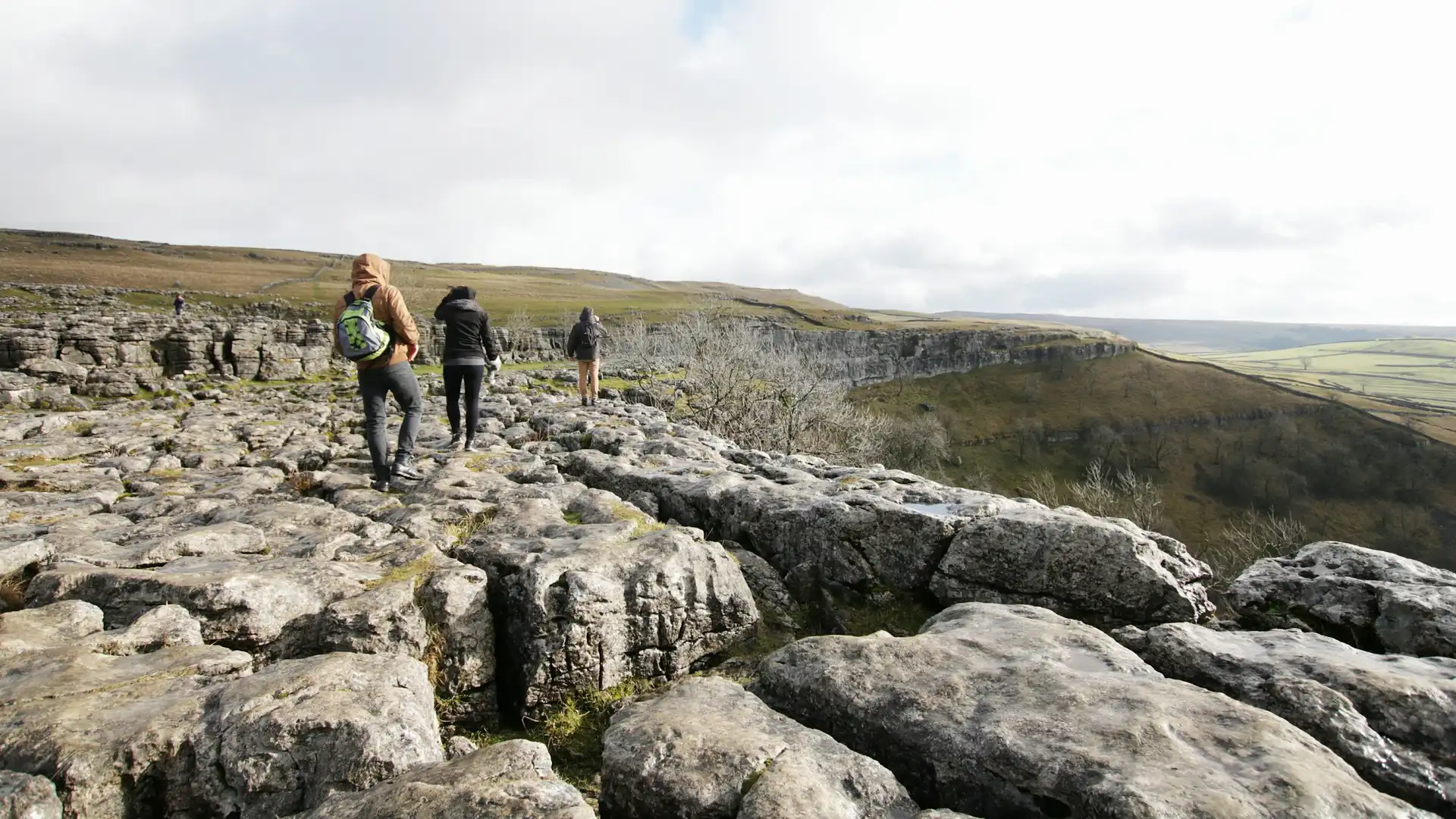 Walkers crossing the limestone pavement at Malham Cove in the Yorkshire Dales National Park, North Yorkshire