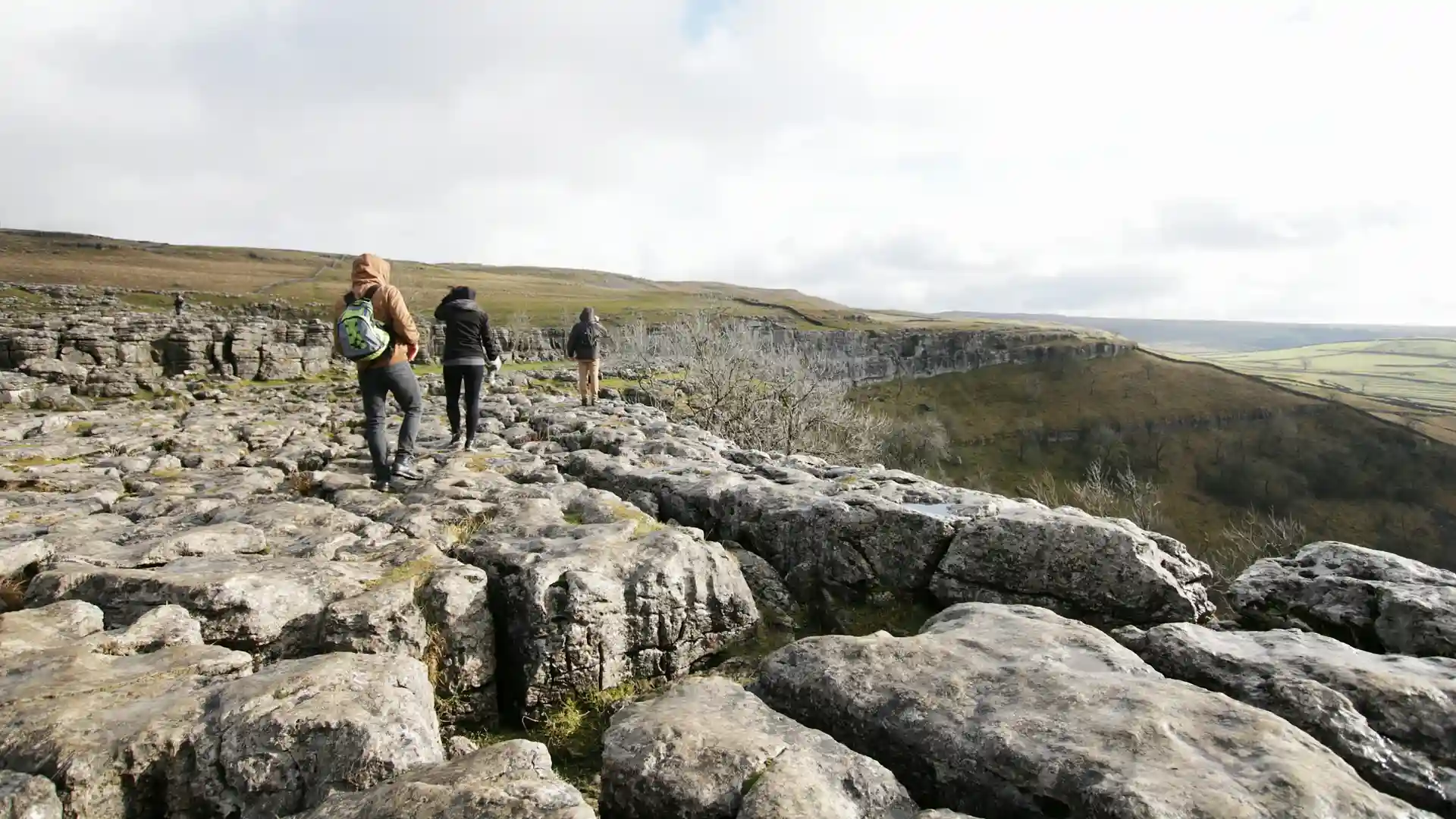 Walkers crossing the limestone pavement at Malham Cove in the Yorkshire Dales National Park, North Yorkshire