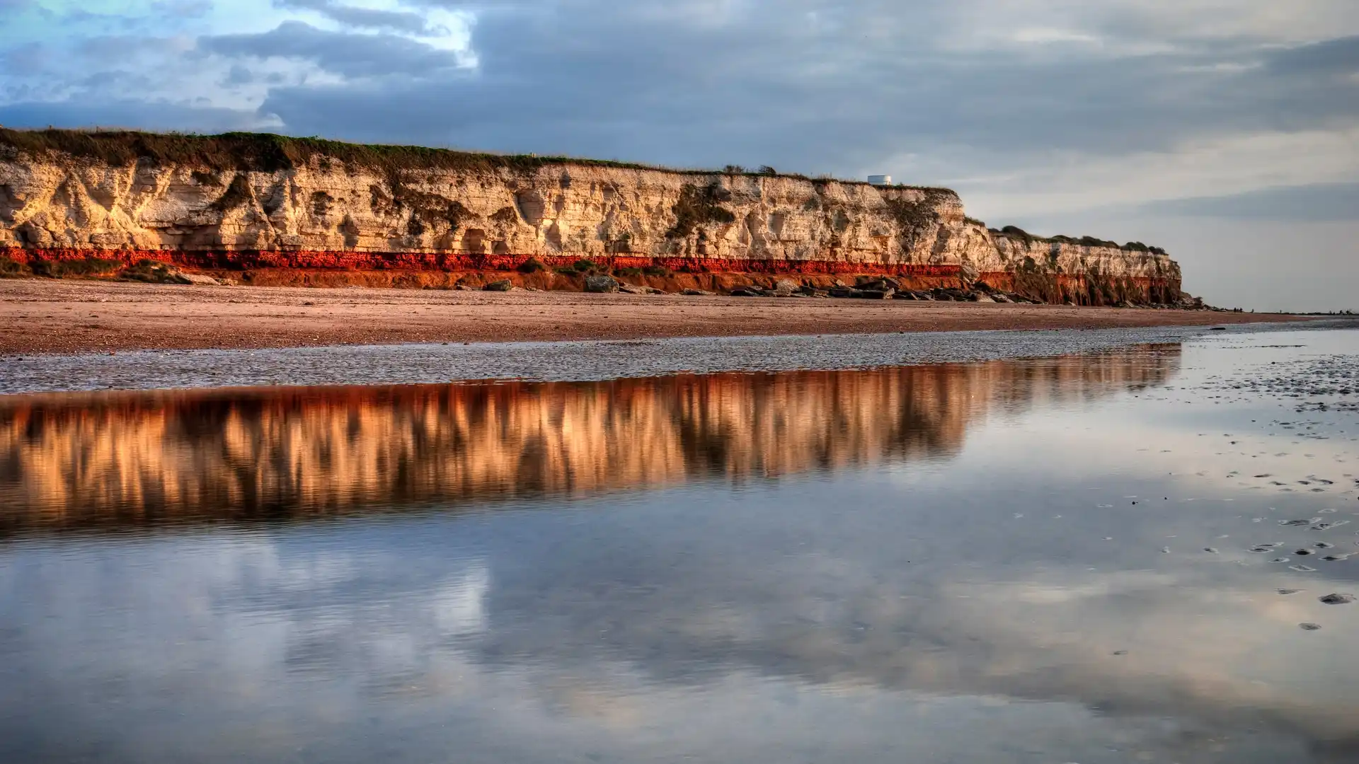 A view of the red and yellow cliffs of Hunstanton beach reflecting onto the sea.