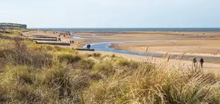 Walkers on the Norfolk Coast Path near Holme-next-the-Sea — a landscape of sand, sea, and sky.