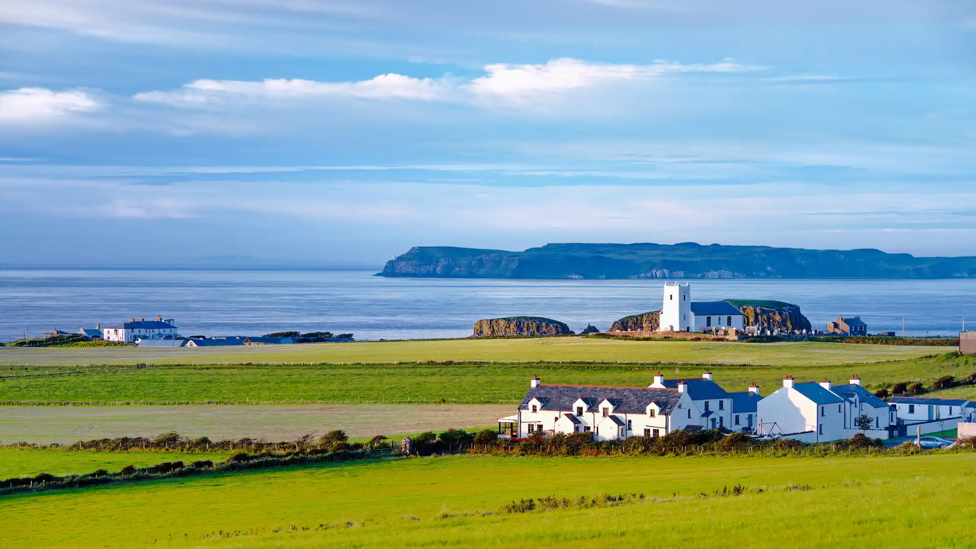 Clifftop church and coastal fields near Bushmills on the Causeway Coast, Northern Ireland, with Atlantic views and walking routes nearby.