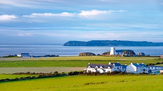 Clifftop church and coastal fields near Bushmills on the Causeway Coast, Northern Ireland, with Atlantic views and walking routes nearby.
