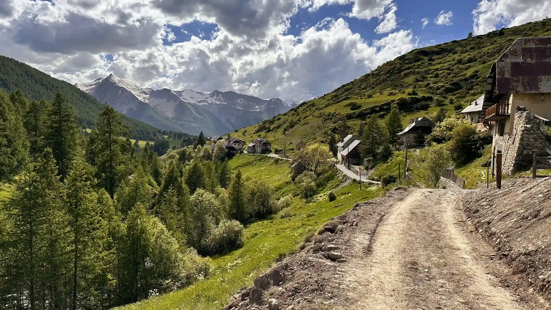 Alpine village and hillside track near Saint-Paul-sur-Ubaye in the Ubaye Valley, surrounded by forested slopes and high peaks.