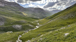 Mountain valley near Beuil with winding stream and grassy slopes in Mercantour National Park.