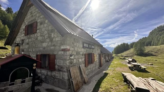 Stone Refuge de Longon mountain hut on the GR5 in Mercantour National Park, surrounded by alpine meadows and larch forest.