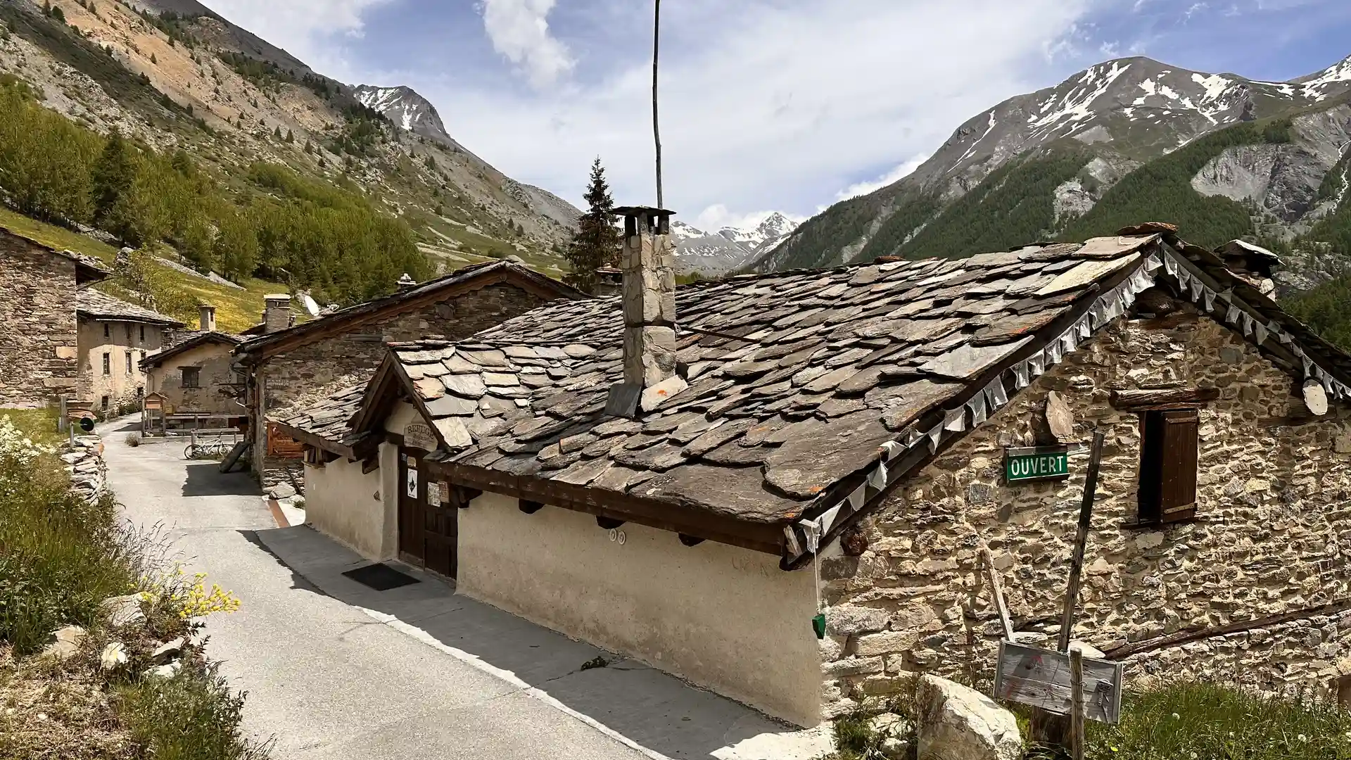 Stone chalet buildings in Maljasset, Haute Ubaye, with slate roofs and high alpine mountains near the GR5 in the southern French Alps.