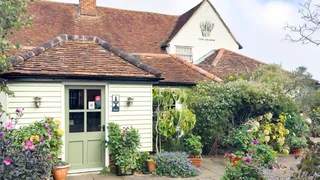 The Crown Inn in Stoke-by-Nayland — a traditional Suffolk country inn with flower-filled courtyard, cream timber walls, and tiled roof, set in the heart of the Dedham Vale National Landscape.